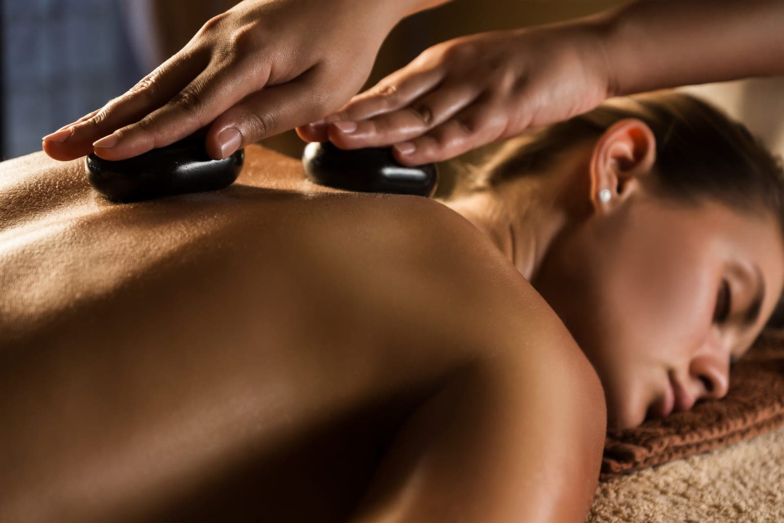 Stenmassage med varma stenar på ryggen